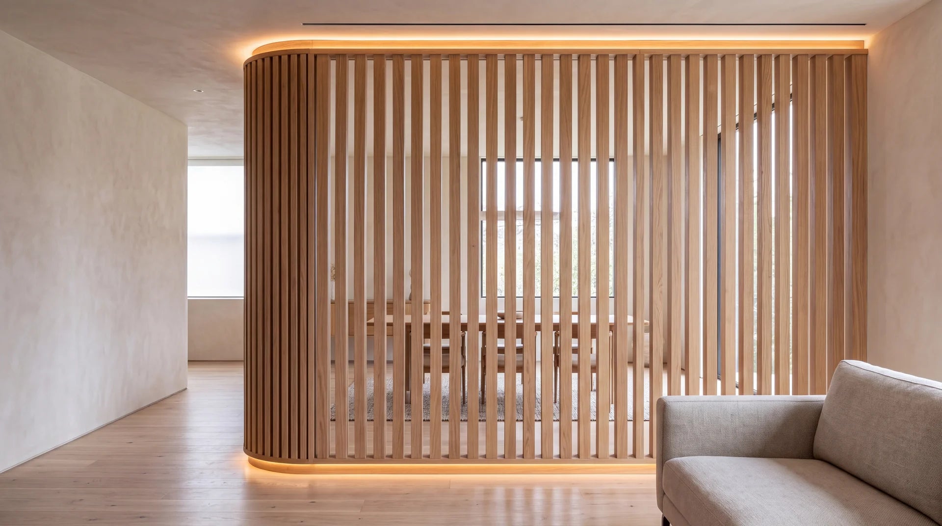 Curved white oak room divider with vertical slats and integrated perimeter light